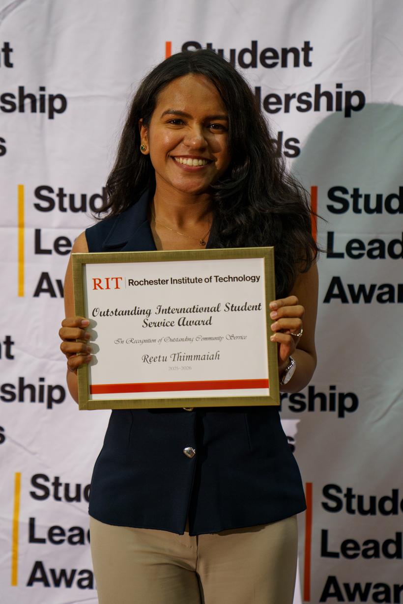 Reetu Thimmaiah holding her Outstanding International Student Service Award certificate at the RIT Student Leadership Awards